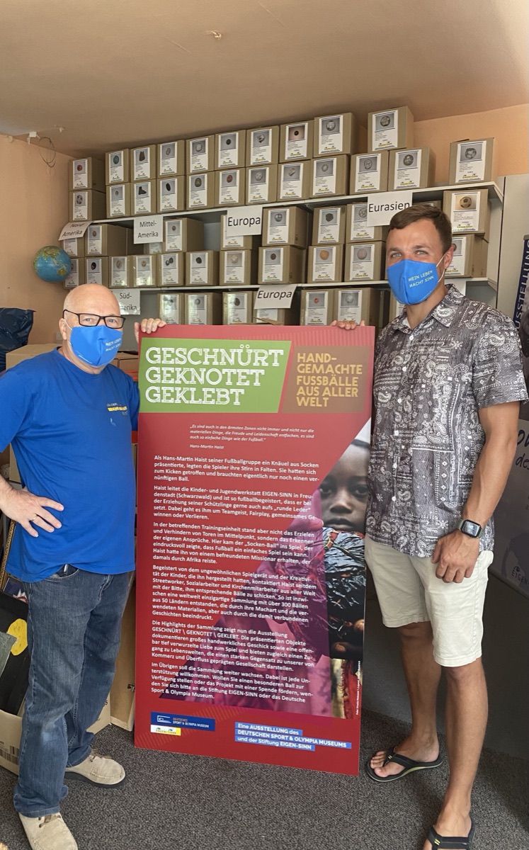 Hans-Martin Haist und Mikel in der Fußballsammlung, vor der Ausstellungs-Tafel „Geschnürt · Geknotet · Geklebt